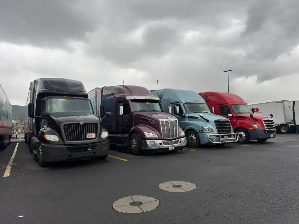 Four semi-trucks parked side by side at a Riverside County fleet yard